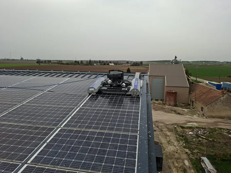 Robot de nettoyage sur une toiture équipée de panneaux solaires, dans un environnement rural